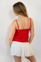 Woman wearing LEMONY cotton jersey lace trim cami top featuring a soft V-neckline with delicate ruffle trim, adjustable spaghetti straps, empire seam detail, and lightweight cotton jersey fabric with comfortable stretch for everyday layering and lounge styling.