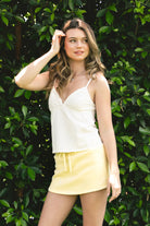 Woman wearing LEMONY cotton jersey lace trim cami top featuring a soft V-neckline with delicate ruffle trim, adjustable spaghetti straps, empire seam detail, and lightweight cotton jersey fabric with comfortable stretch for everyday layering and lounge styling.