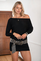 Woman wearing a black off-shoulder dress with a silver belt.