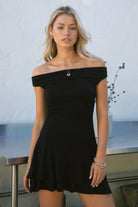 Woman wearing TIC TOC DC31642BA RAVAYA off-the-shoulder mini dress featuring ruched sides and a frill hemline in soft rayon spandex fabric