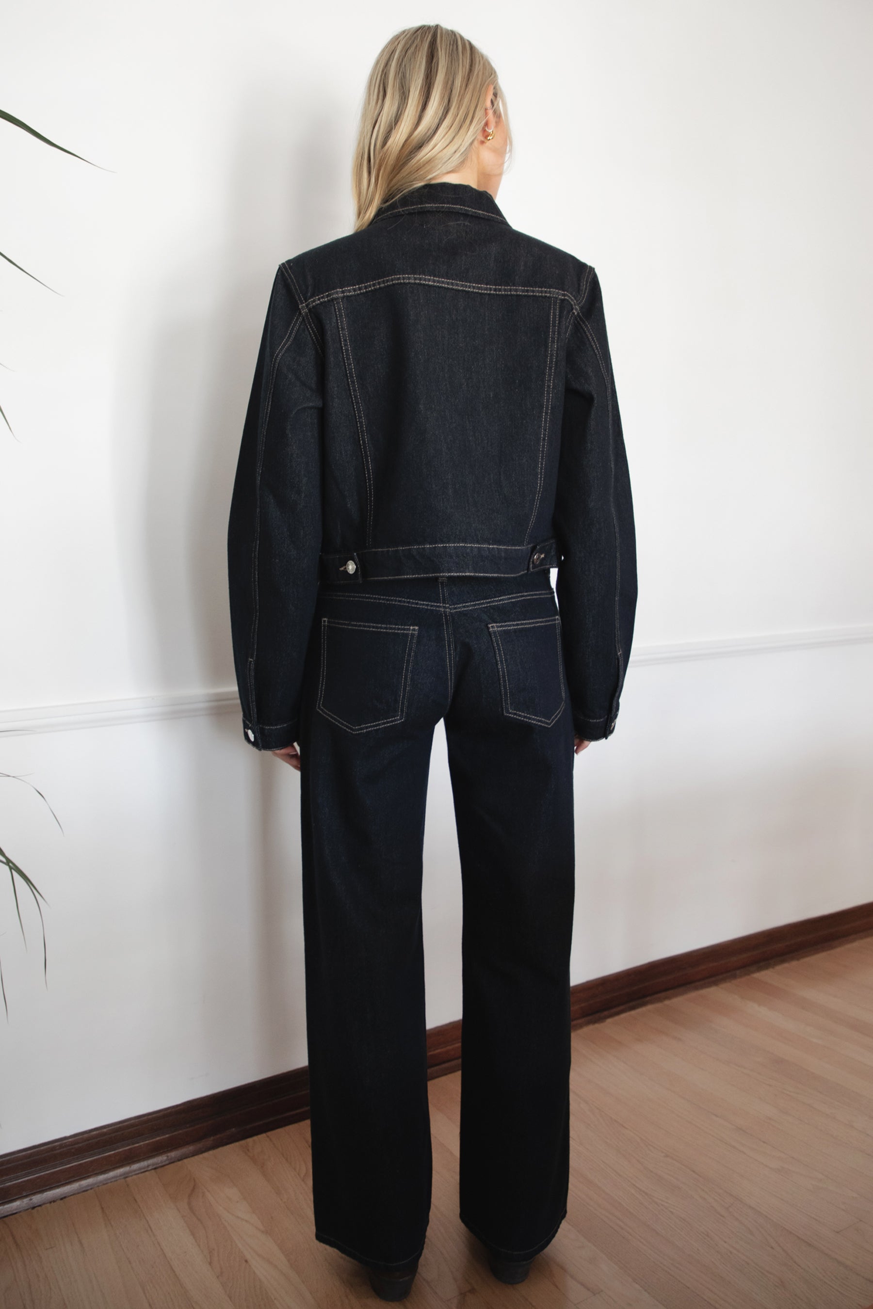 Woman wearing TIC TOC PF31703 MILLS selvedge denim straight leg pants in dark blue wash with a low-rise waist and wide-leg silhouette with a matching jackte in an indoor setting. 