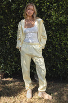 Woman wearing the TIC TOC PH26027 DOVE pale yellow high waist sweatpants featuring an elastic waistband, deep side pockets, and tapered ankle hem with a matching top. 