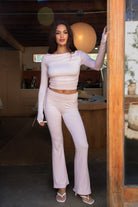 Woman wearing the TIC TOC PH30646BA CORA blush fold over flare leggings featuring a low rise waistline, smooth stretch fabric, and subtle flare hem with matching top in front of a doorway entrance. 