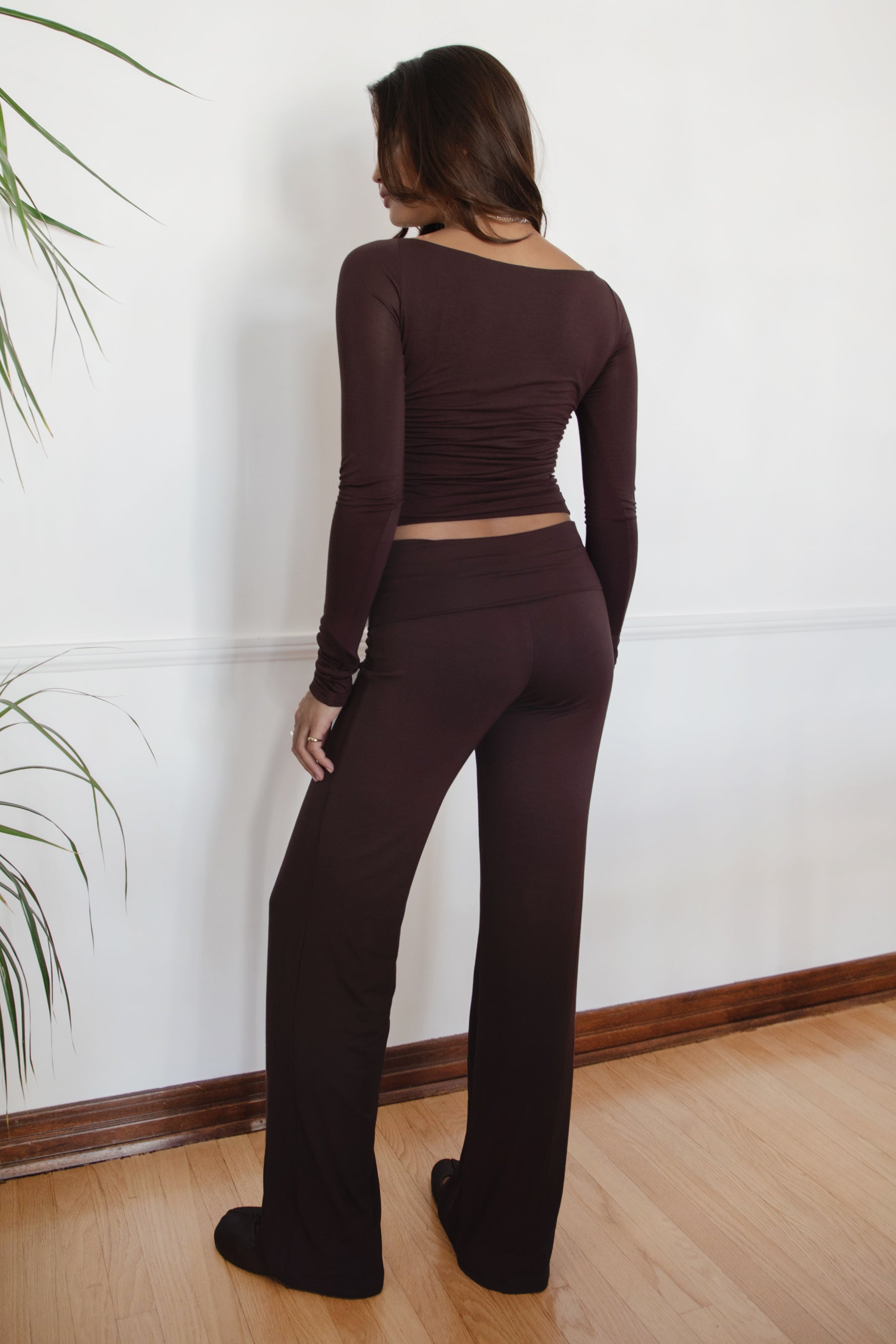 Woman wearing the TIC TOC PH31588BA SORA brown fold over straight leg leggings featuring a low rise waistline, smooth stretch fabric, and straight leg finish with the matching top against a white wall.