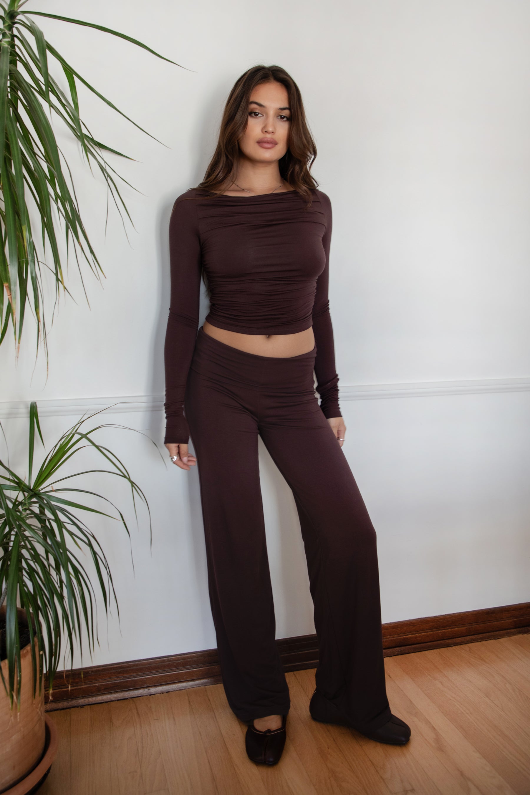 Woman wearing the TIC TOC PH31588BA SORA brown fold over straight leg leggings featuring a low rise waistline, smooth stretch fabric, and straight leg finish with the matching top against a white wall.