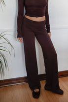 Woman wearing the TIC TOC PH31588BA SORA brown fold over straight leg leggings featuring a low rise waistline, smooth stretch fabric, and straight leg finish with the matching top against a white wall.