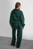 Woman wearing the TIC TOC PJ30241 LANI forrest green cloud fleece wide leg sweatpants featuring a straight leg silhouette, drawcord waistband, and side pockets paired with a matching sweater.