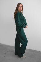 Woman wearing the TIC TOC PJ30241 LANI forrest green cloud fleece wide leg sweatpants featuring a straight leg silhouette, drawcord waistband, and side pockets paired with a matching sweater.