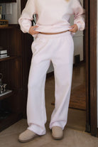 Woman wearing the TIC TOC PJ30241 LANI pale pink cloud fleece wide leg sweatpants featuring a straight leg silhouette, drawcord waistband, and side pockets paired with a matching hoodie. 