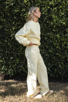 Woman wearing the TIC TOC PJ30241 LANI pale yellow cloud fleece wide leg sweatpants featuring a straight leg silhouette, drawcord waistband, and side pockets paired with a matching sweater.