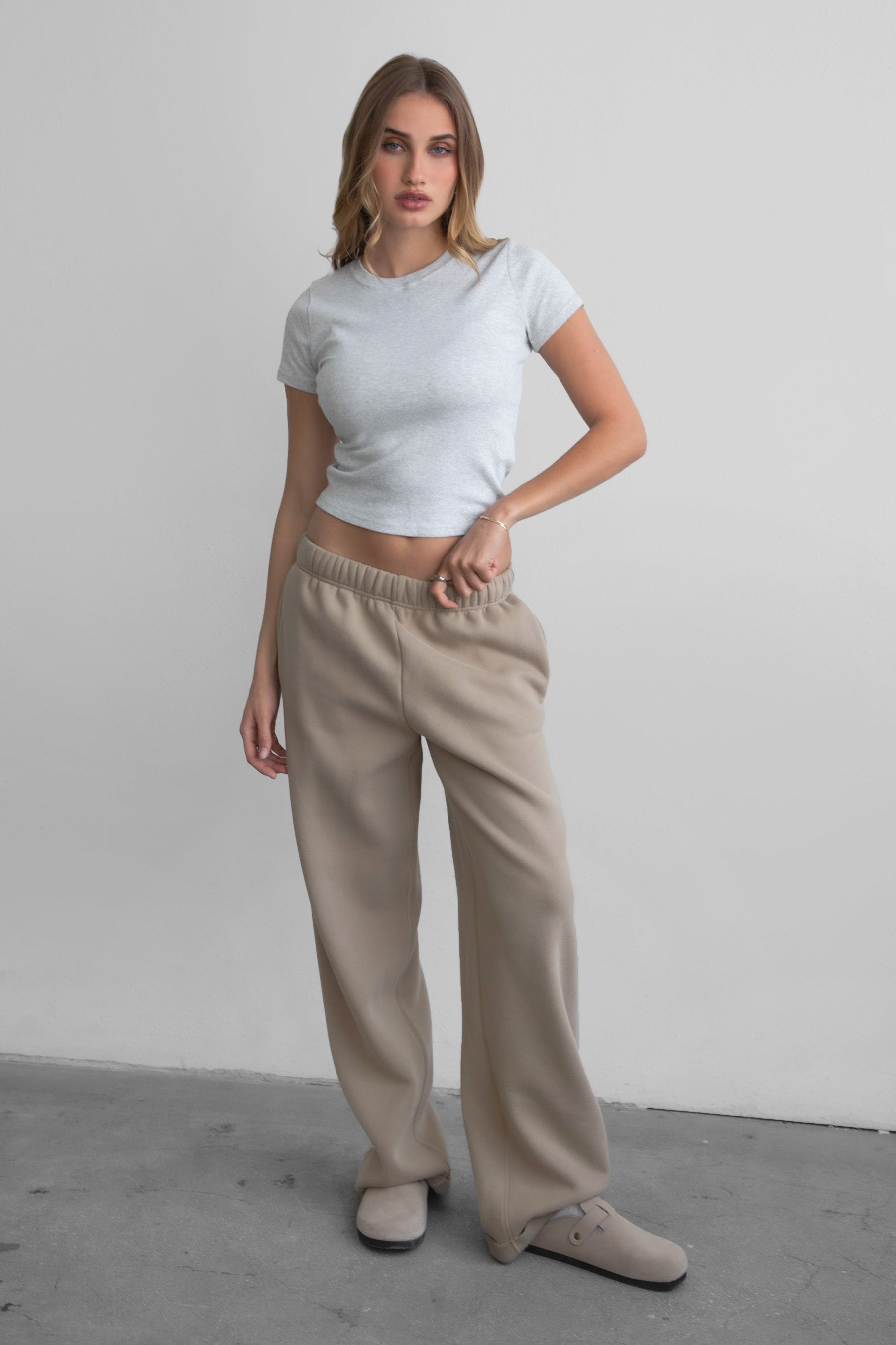 Woman wearing the TIC TOC PJ30241 LANI taupe cloud fleece wide leg sweatpants featuring a straight leg silhouette, drawcord waistband, and side pockets paired with a baby tee. 