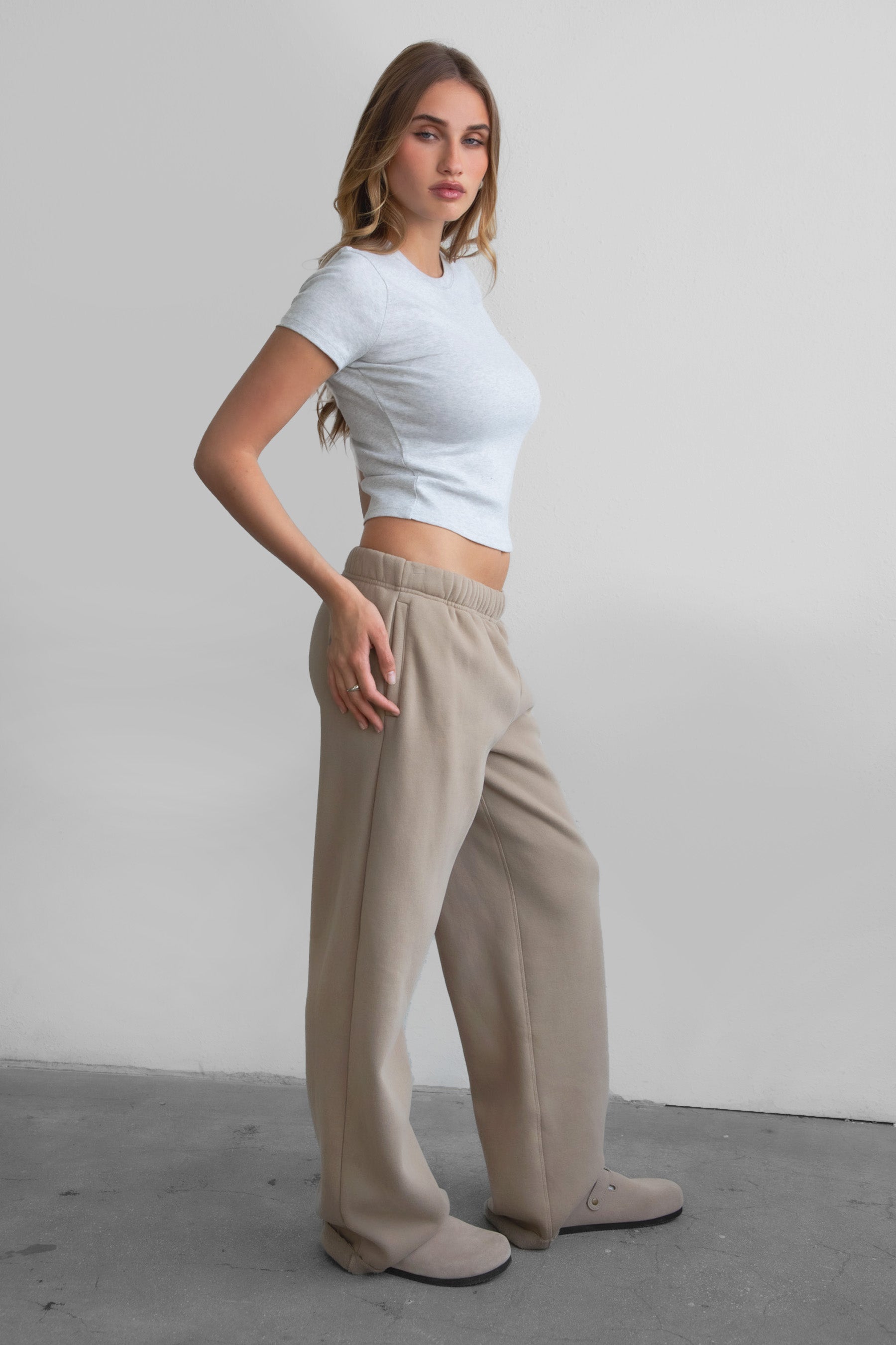 Woman wearing the TIC TOC PJ30241 LANI taupe cloud fleece wide leg sweatpants featuring a straight leg silhouette, drawcord waistband, and side pockets paired with a baby tee. 