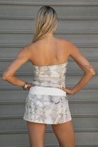 Woman wearing TIC TOC SJ31673 AVERY light woodland camo fleece mini skort with drawstring waist and cloud fleece interior paired with a macthing strapless top in an outdoor area