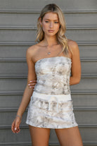 Woman wearing TIC TOC SJ31673 AVERY light woodland camo fleece mini skort with drawstring waist and cloud fleece interior paired with a macthing strapless top in an outdoor area