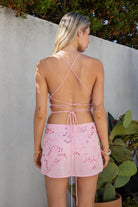 Model wearing the TIC TOC SL31480 VEDA pink chiffon beaded low-rise mini skort featuring hand-beaded floral embroidery, chiffon overlay, and built-in shorts with a matching cami top in an outdoor setting. 