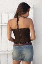 Woman wearing TIC TOC TA30581 RAELYNN embroidered western corset top with halter neckline, flame embroidery, gold studs, and lace-up front paired with a denim mini skirt