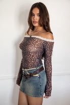 Woman wearing the TIC TOC TC31579 BAMBELLE off-the-shoulder top featuring a deer-inspired mesh print, lace trim neckline, and long bell sleeves paired with a distressed denim mini skirt