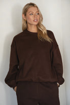 Woman wearing a brown sweater against a white background