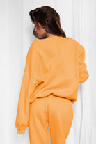 Person wearing an orange outfit against a white curtain background