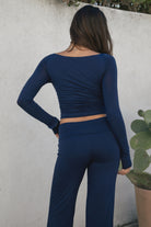 Woman wearing the TIC TOC TH30643 JOLINA navy  core basic long sleeve top featuring high boat neckline, and ruched detailing along the bodice with matching bottoms oudoors. 