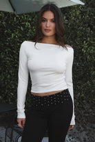 Model wearing TIC TOC TH31573BA RAYAE asymmetric off-the-shoulder jersey top with wide neckline and draped long sleeves paired with polka dot black capri pants in an outdoor setting. 