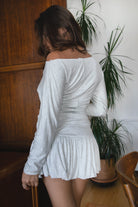 Woman wearing the TIC TOC TH31856BA SORA heather white asymmetric off-the-shoulder long sleeve top featuring a slouchy cropped fit, wide boat neckline, and soft stretch fabric with matching skirt.