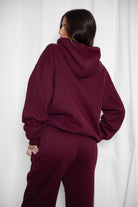 Woman wearing the TIC TOC TJ31007 DAMI black cherry cloud fleece oversized hoodie featuring a dropped shoulder design, kangaroo pocket, and ribbed cuffs with matching bottoms.