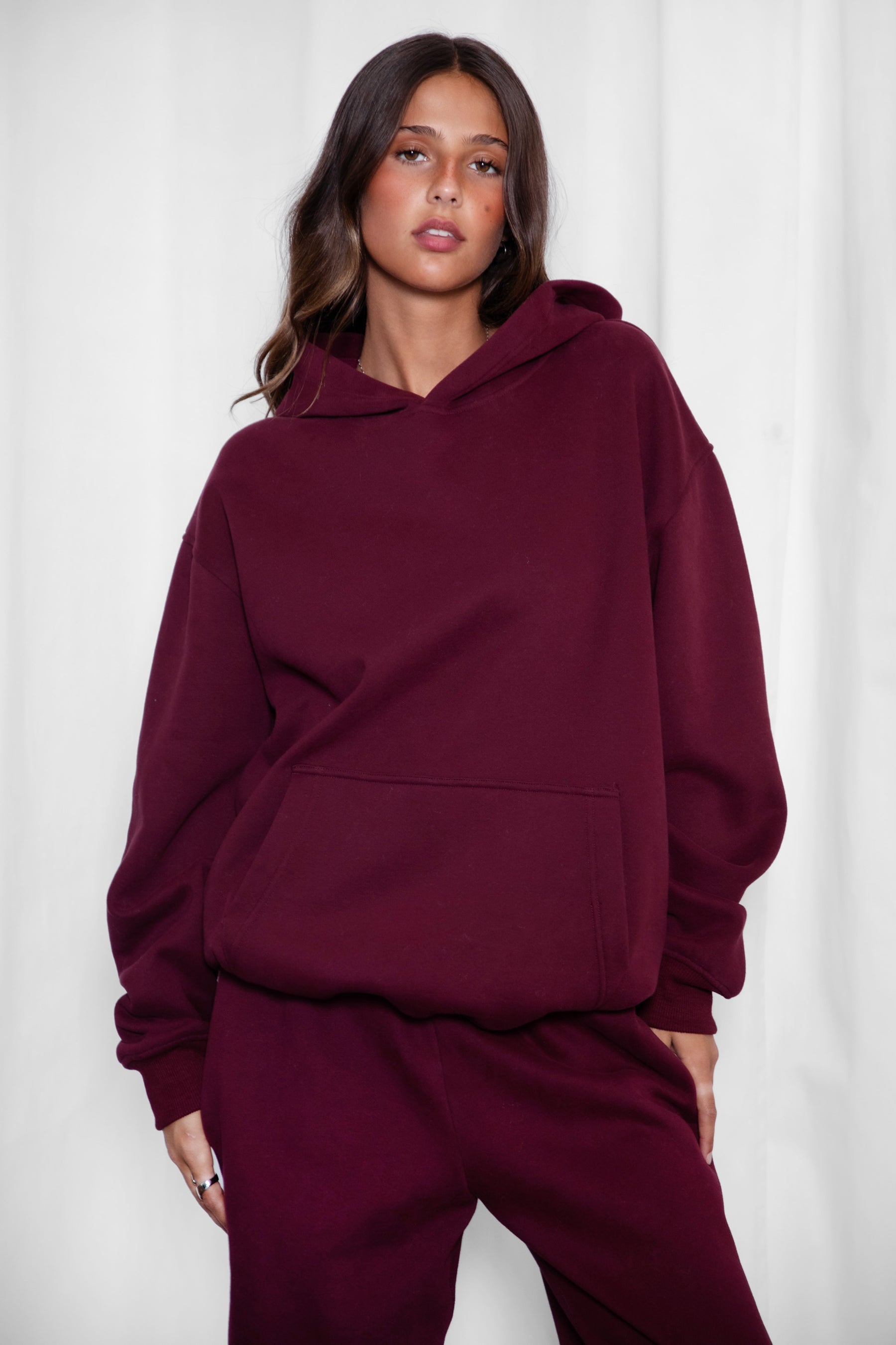 Woman wearing the TIC TOC TJ31007 DAMI black cherry cloud fleece oversized hoodie featuring a dropped shoulder design, kangaroo pocket, and ribbed cuffs with matching bottoms.