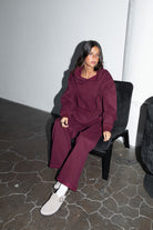 Woman wearing the TIC TOC TJ31007 DAMI black cherry cloud fleece oversized hoodie featuring a dropped shoulder design, kangaroo pocket, and ribbed cuffs with matching bottoms.