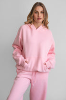 Woman wearing the TIC TOC TJ31007 DAMI blush cloud fleece oversized hoodie featuring a dropped shoulder design, kangaroo pocket, and ribbed cuffs with matching bottoms.