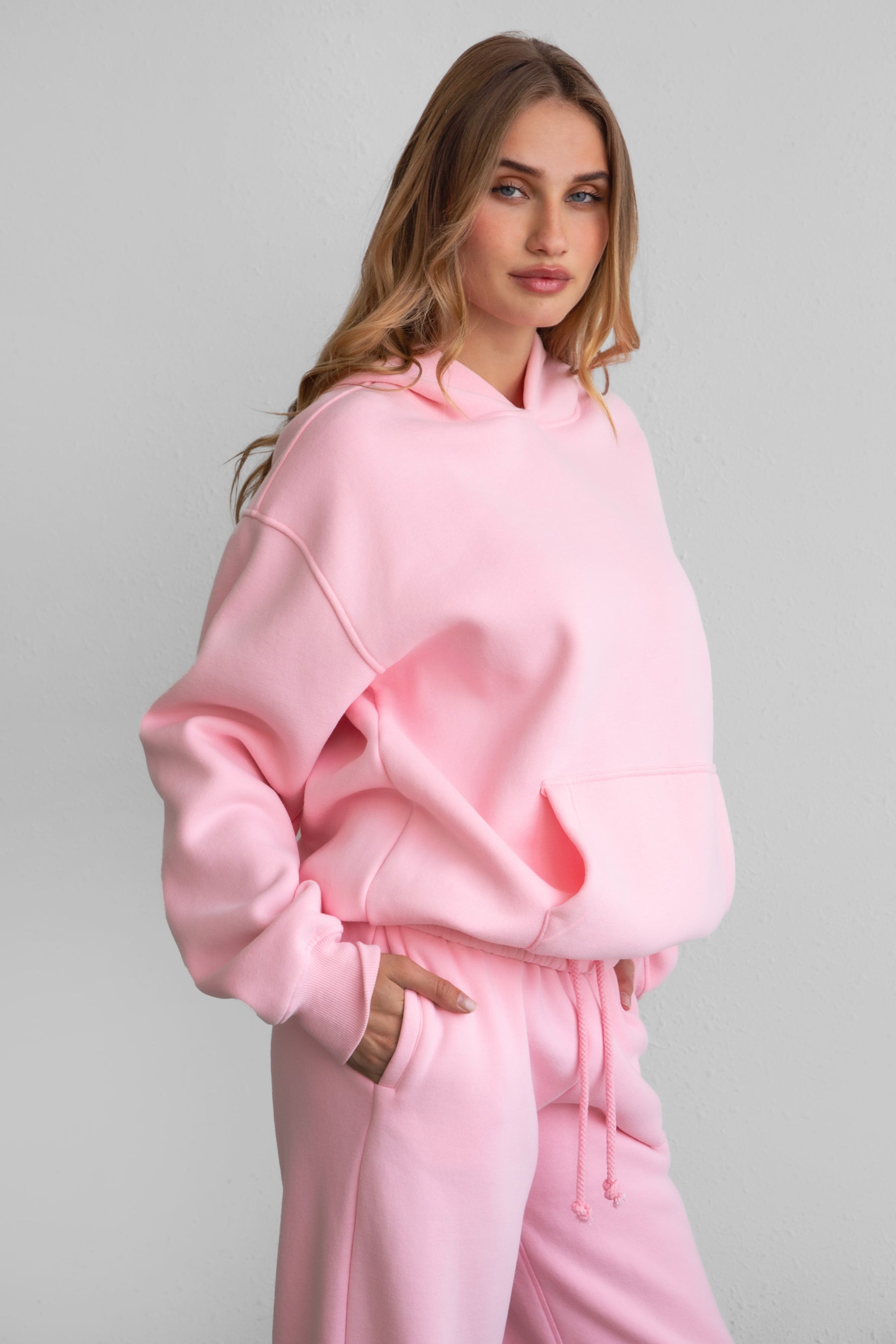 Woman wearing the TIC TOC TJ31007 DAMI blush cloud fleece oversized hoodie featuring a dropped shoulder design, kangaroo pocket, and ribbed cuffs with matching bottoms.