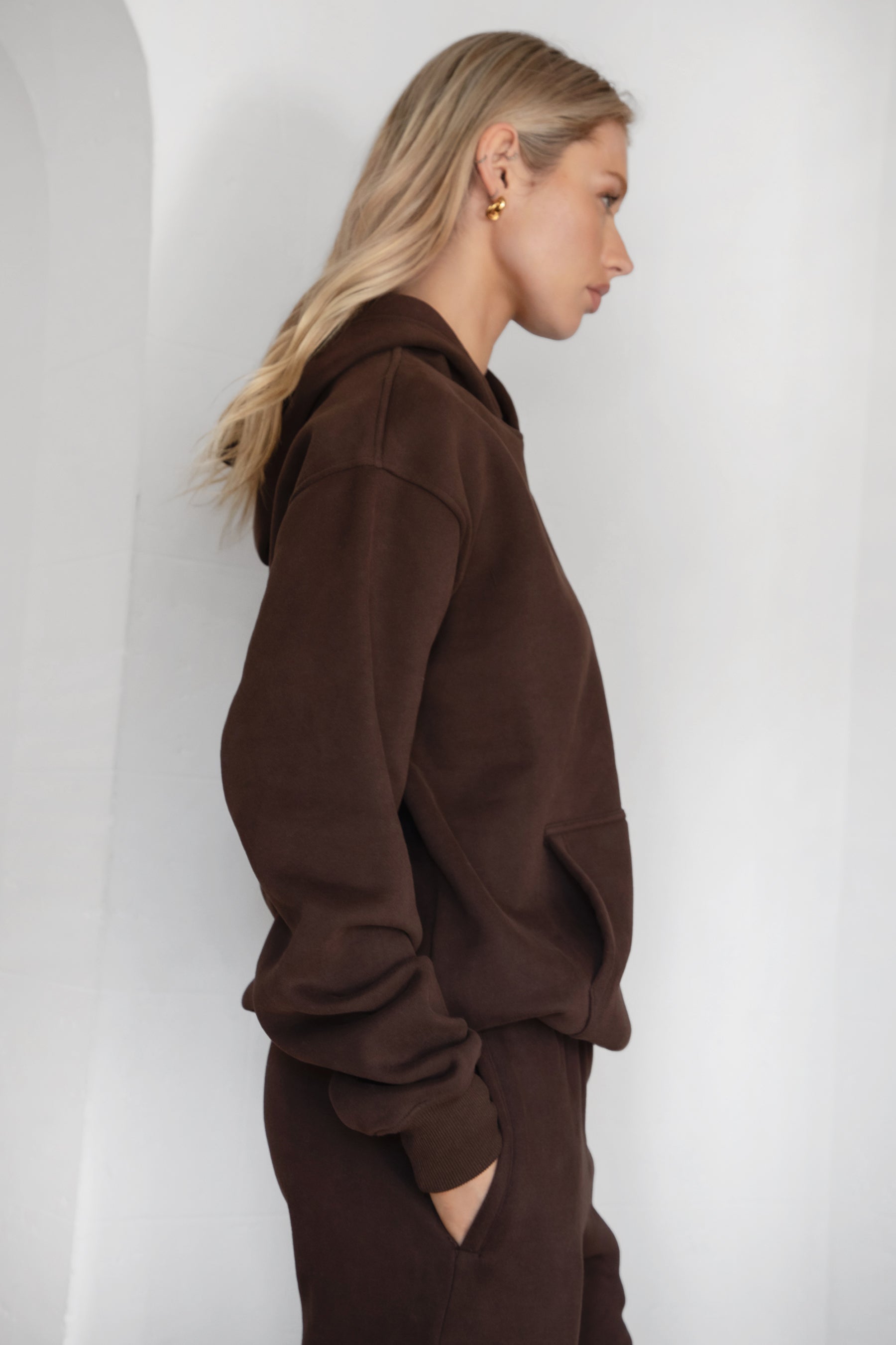 Woman wearing the TIC TOC TJ31007 DAMI dark brown cloud fleece oversized hoodie featuring a dropped shoulder design, kangaroo pocket, and ribbed cuffs with matching bottoms.