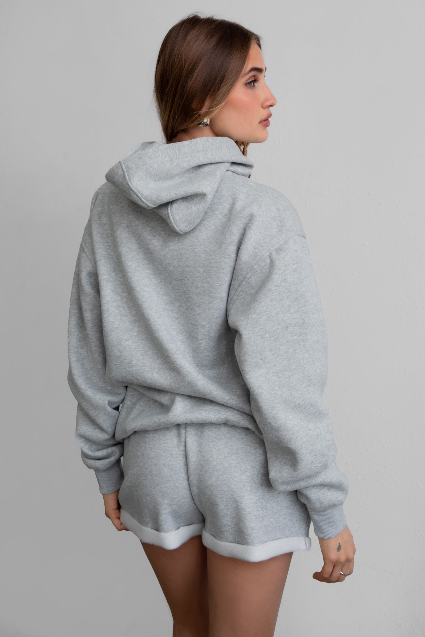 Woman wearing the TIC TOC TJ31007 DAMI heather grey cloud fleece oversized hoodie featuring a dropped shoulder design, kangaroo pocket, and ribbed cuffs with matching bottoms.