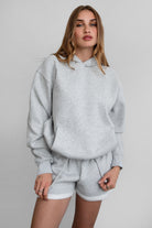 Woman wearing the TIC TOC TJ31007 DAMI heather grey cloud fleece oversized hoodie featuring a dropped shoulder design, kangaroo pocket, and ribbed cuffs with matching bottoms.
