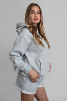 Woman wearing the TIC TOC TJ31007 DAMI heather grey cloud fleece oversized hoodie featuring a dropped shoulder design, kangaroo pocket, and ribbed cuffs with matching bottoms.