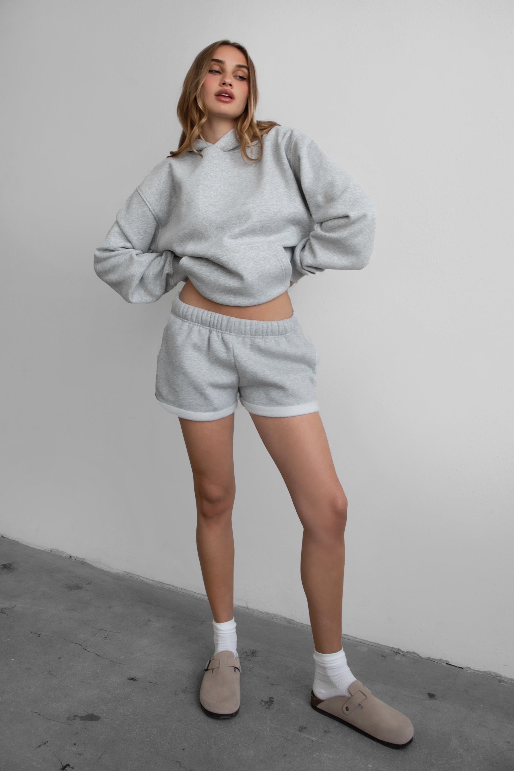 Woman wearing the TIC TOC TJ31007 DAMI heather grey cloud fleece oversized hoodie featuring a dropped shoulder design, kangaroo pocket, and ribbed cuffs with matching bottoms.