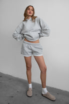 Woman wearing the TIC TOC TJ31007 DAMI heather grey cloud fleece oversized hoodie featuring a dropped shoulder design, kangaroo pocket, and ribbed cuffs with matching bottoms.