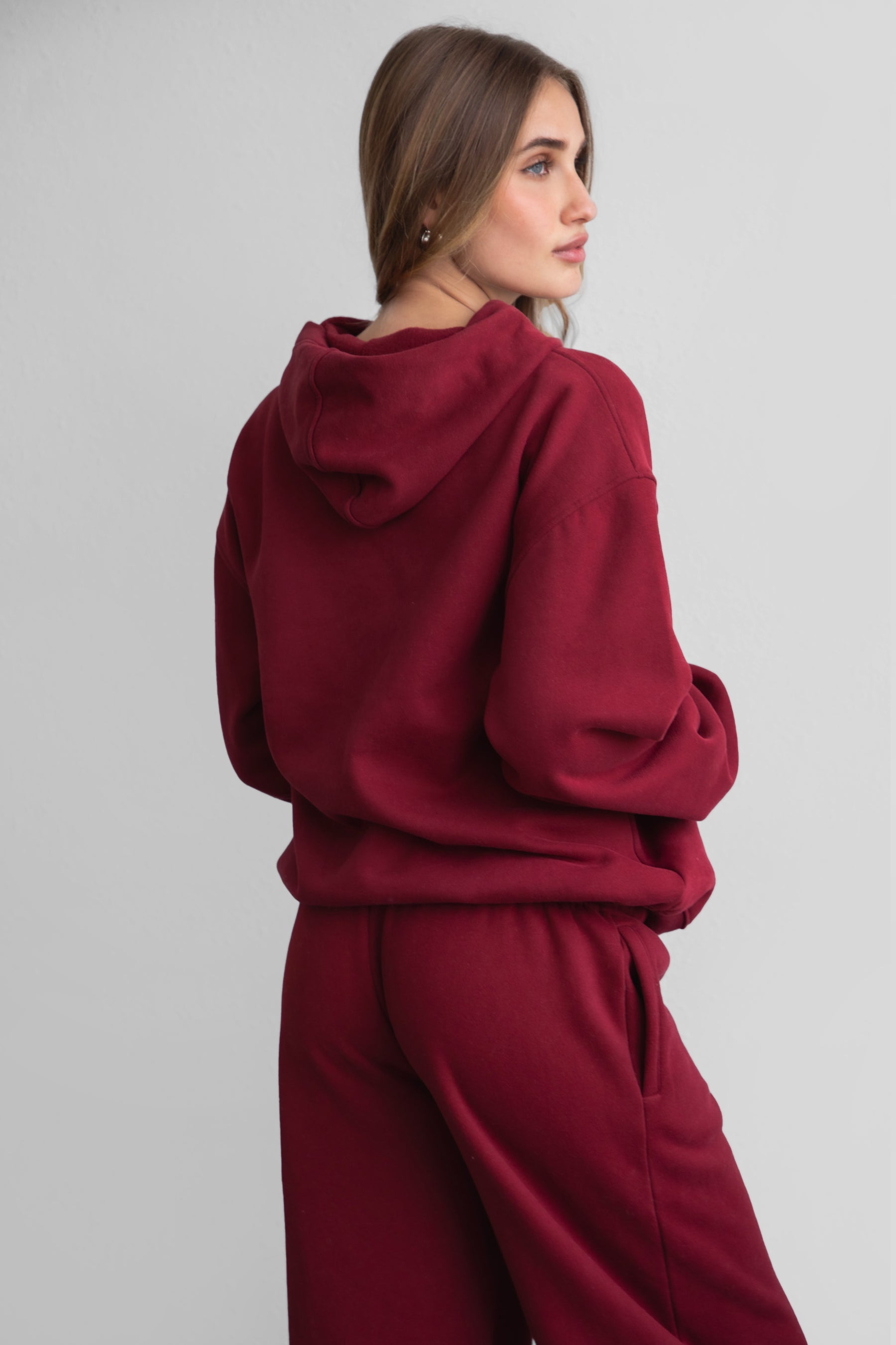 Woman wearing the TIC TOC TJ31007 DAMI maroon cloud fleece oversized hoodie featuring a dropped shoulder design, kangaroo pocket, and ribbed cuffs with matching bottoms.