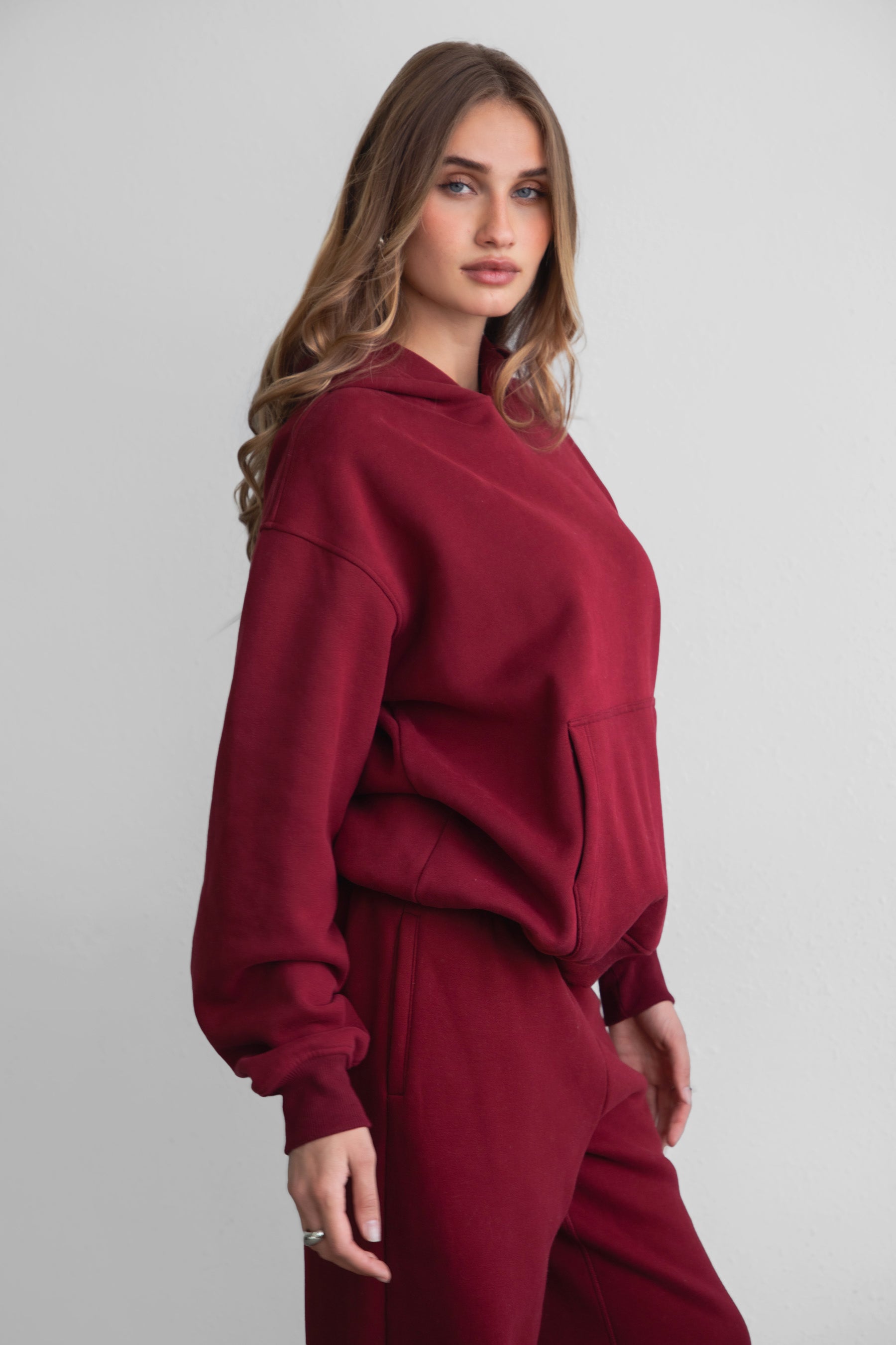 Woman wearing the TIC TOC TJ31007 DAMI maroon cloud fleece oversized hoodie featuring a dropped shoulder design, kangaroo pocket, and ribbed cuffs with matching bottoms.