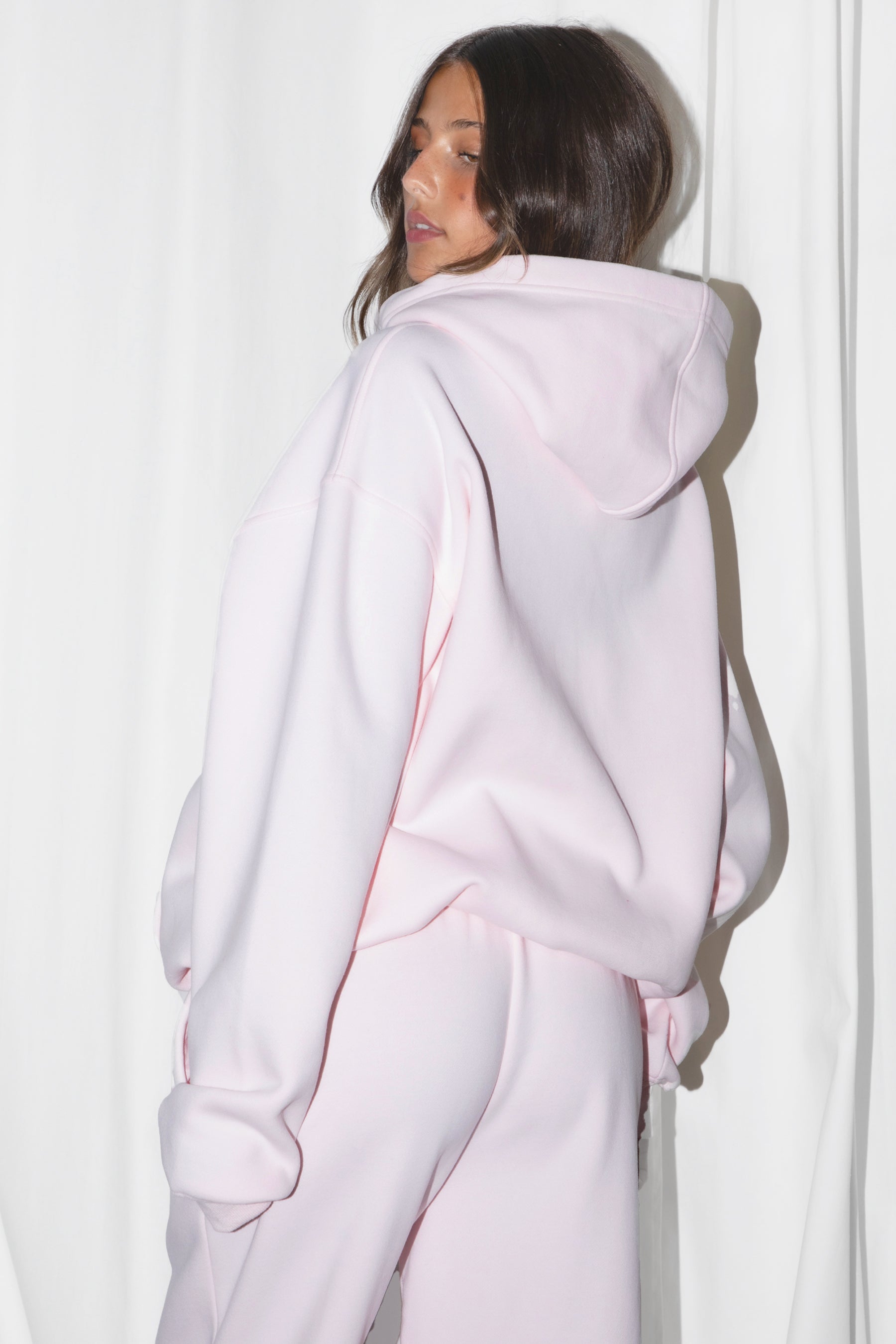 Woman wearing the TIC TOC TJ31007 DAMI pale pink cloud fleece oversized hoodie featuring a dropped shoulder design, kangaroo pocket, and ribbed cuffs with matching bottoms.