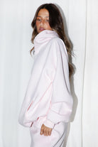 Woman wearing the TIC TOC TJ31007 DAMI pale pink cloud fleece oversized hoodie featuring a dropped shoulder design, kangaroo pocket, and ribbed cuffs with matching bottoms.