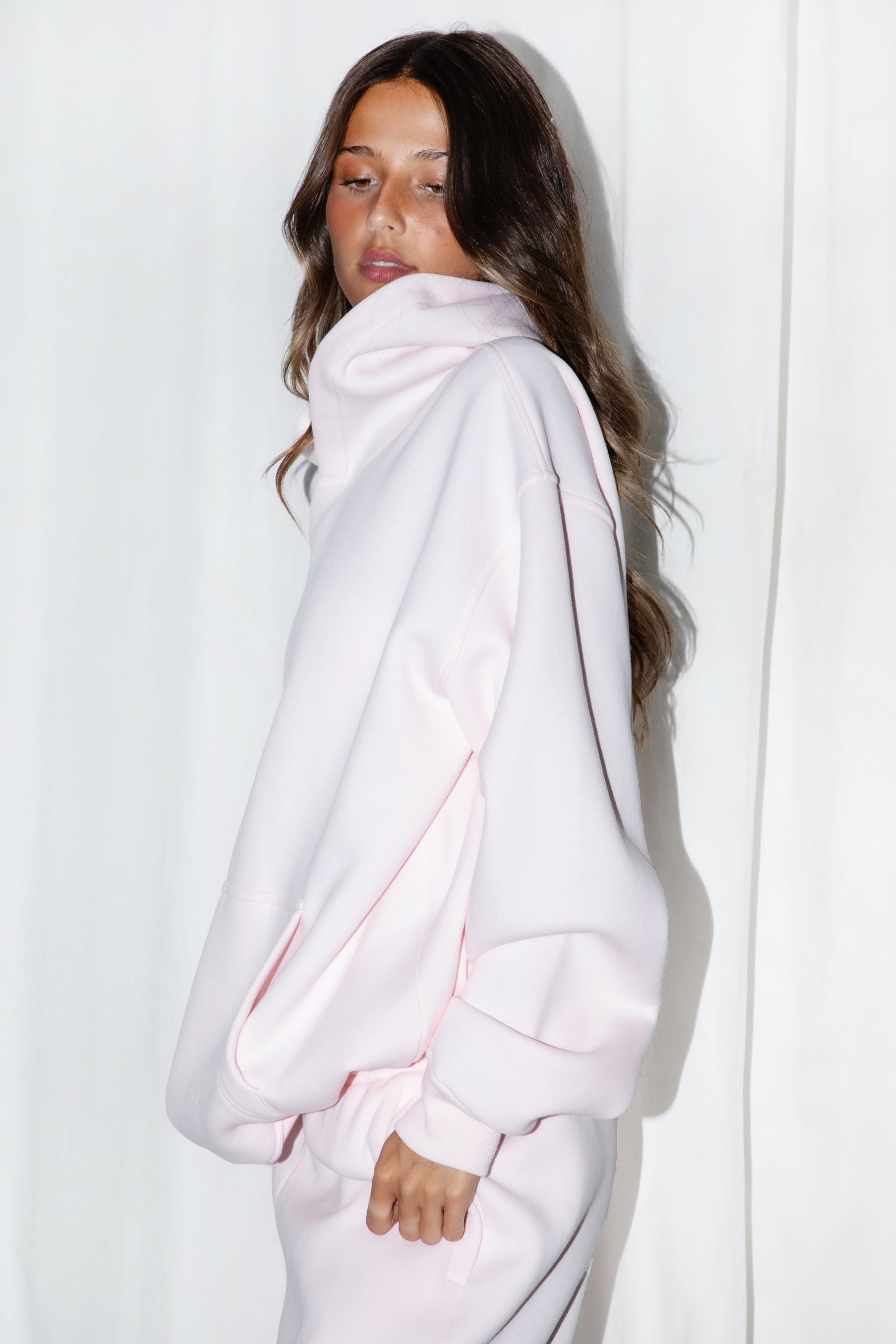 Woman wearing the TIC TOC TJ31007 DAMI pale pink cloud fleece oversized hoodie featuring a dropped shoulder design, kangaroo pocket, and ribbed cuffs with matching bottoms.