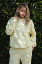 Woman wearing the TIC TOC TJ31007 DAMI pale yellow cloud fleece oversized hoodie featuring a dropped shoulder design, kangaroo pocket, and ribbed cuffs with matching bottoms.