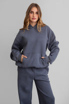 Woman wearing the TIC TOC TJ31007 DAMI steel grey cloud fleece oversized hoodie featuring a dropped shoulder design, kangaroo pocket, and ribbed cuffs with matching bottoms.