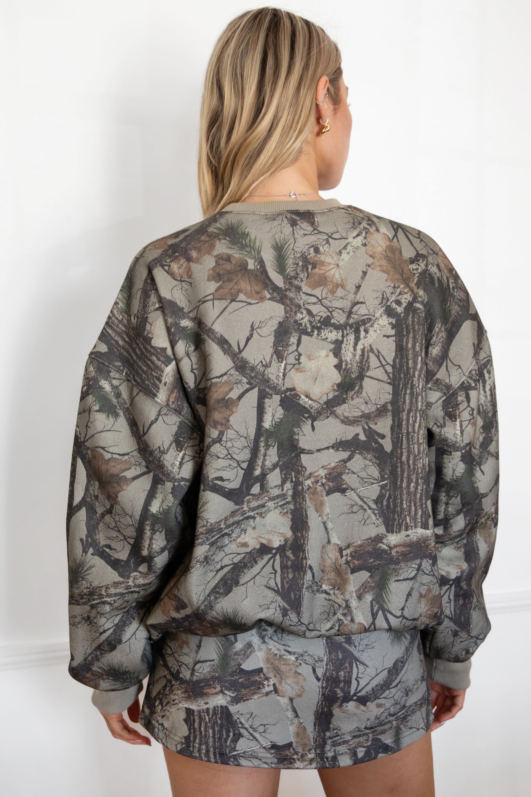 Woman wearing a camouflage outfit against a white background