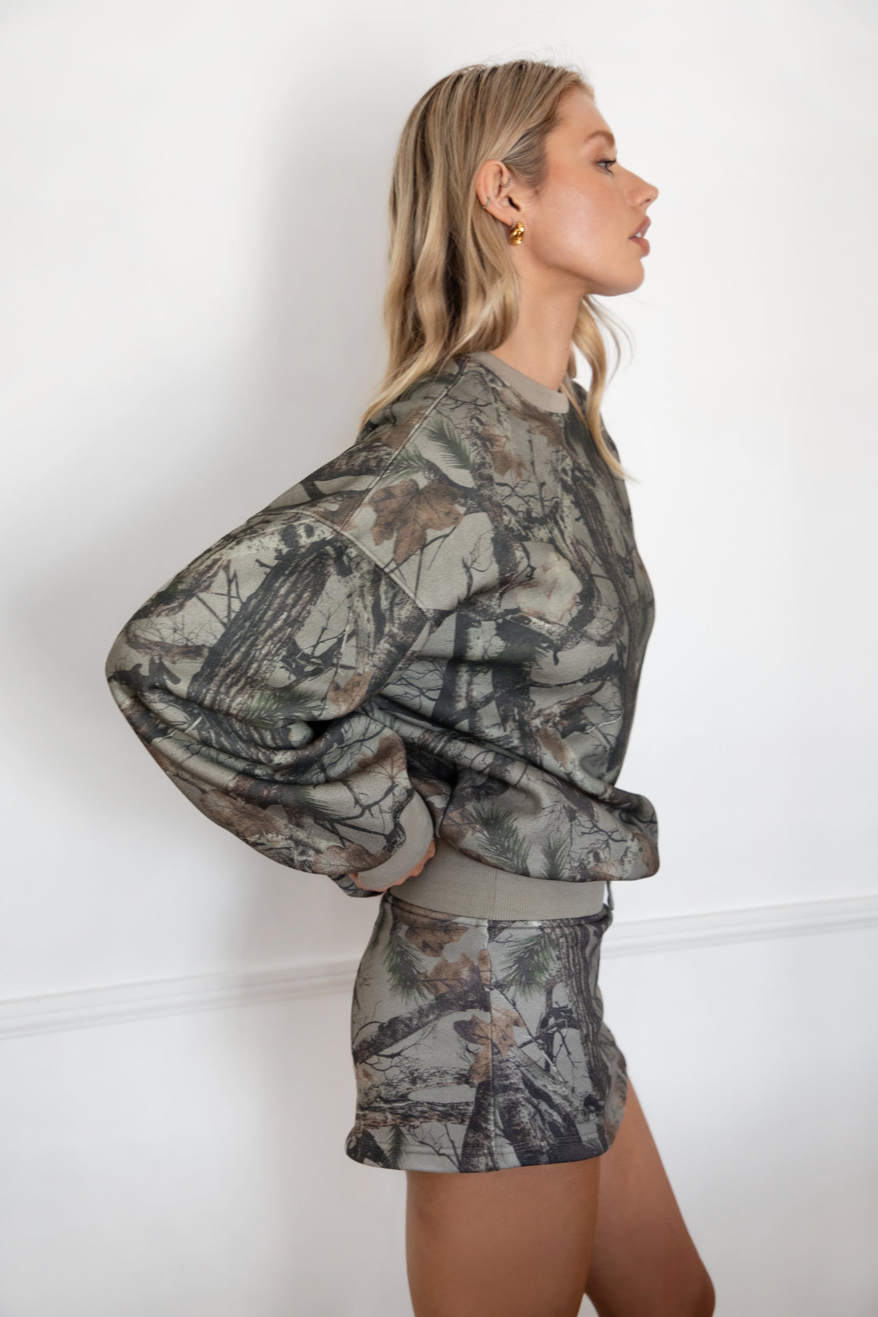 Woman wearing a camouflage outfit against a white background