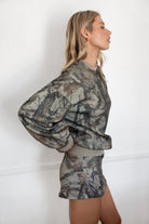 Woman wearing a camouflage outfit against a white background