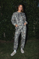 Woman wearing TIC TOC TJ31427 ELK woodland camo fleece crew neck sweatshirt with oversized fit, ribbed cuffs, and hem with matching bottoms against a dark background