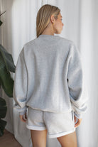 Woman wearing the TIC TOC TJ31656 LANI heather grey cloud fleece crew neck pullover sweatshirt featuring dropped shoulders, ribbed trim, and cozy fleece fabric with the matching bottoms .