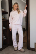 Woman wearing the TIC TOC TJ31656 LANI pale pink cloud fleece crew neck pullover sweatshirt featuring dropped shoulders, ribbed trim, and cozy fleece fabric with the matching bottoms indoors. 